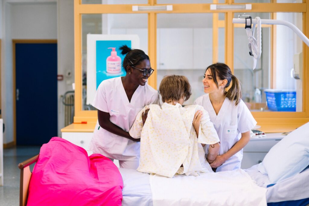 Deux élèves en blouse blanche accompagnent un enfant en salle de travaux pratiques