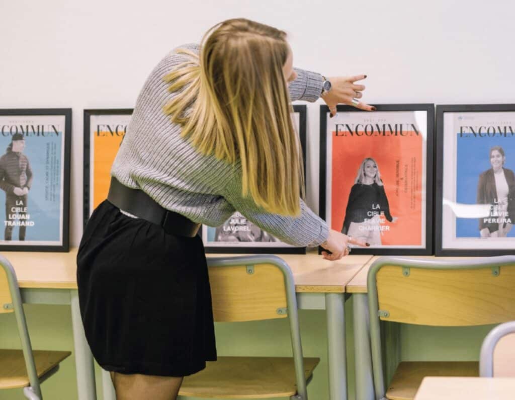 Une étudiante observe un mur de couvertures de magazines encadrées