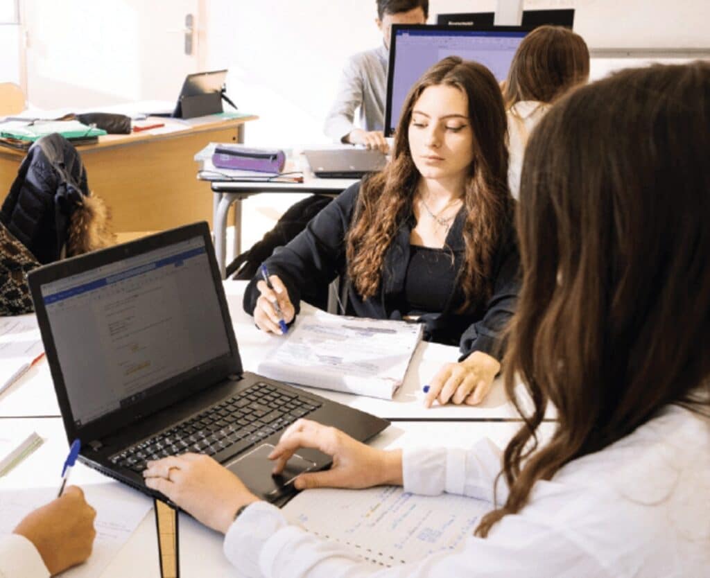 Une étudiante prend des notes à côté de son ordinateur portable en classe