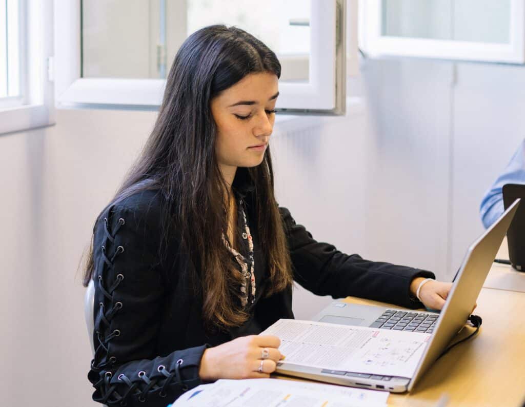 Une étudiante concentrée sur son ordinateur portable en salle de classe