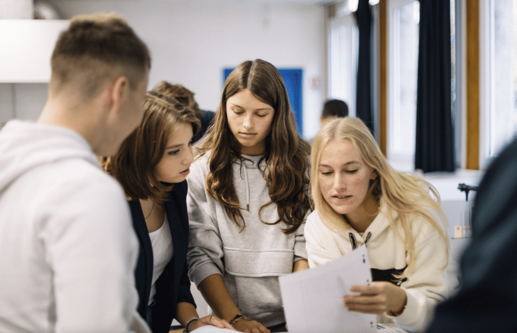 Quatre élèves penchés ensemble sur un même document
